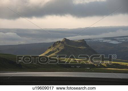 Stock Photo - Craggy mountain rising above verdant grassland. Fotosearch