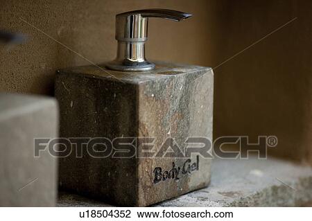 Stock Image - Cube stone bathroom body gel dispenser with a metal pump. Fotosearch