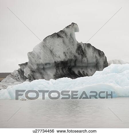 Stock Photograph - Dirty and clean icebergs floating in glacial lake. Fotosearch