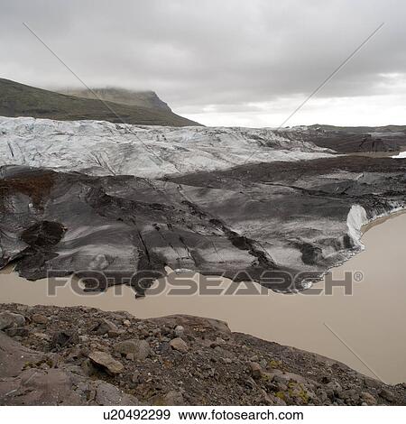Dirty glacier melting into lake at shoreline, below misty mountain valley View Large Photo Image Stock Photo - Dirty glacier melting into lake at shoreline, below misty mountain valley. Fotosearch