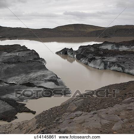 Stock Image - Dusty dirty icebergs on shore of glacial lake. Fotosearch