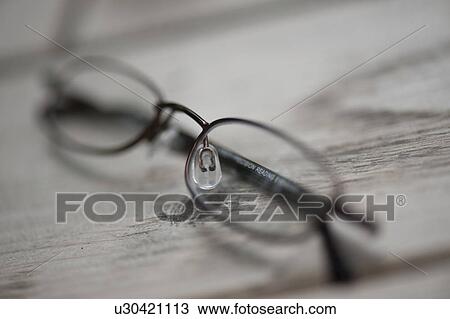 Stock Image - Eye glasses resting on a wooden plank. Fotosearch