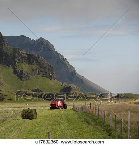 Fenced farmland with hay bailer below craggy mountain View Large Photo Image Stock Image - Fenced farmland with hay bailer below craggy mountain. Fotosearch