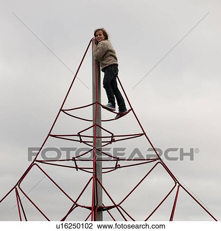 Stock Image - Girl climbing atop triangular rope structure. Fotosearch