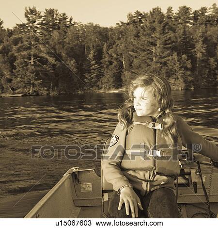 Stock Image - Girl in a boat wearing a life jacket at Lake of the Woods, Ontario. Fotosearch