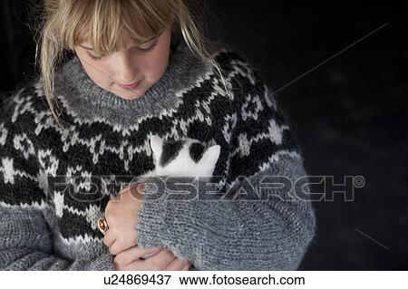 Stock Photo - Girl in a handknit Icelandic sweater holding a fluffy bank and white kitten in Iceland. Fotosearch