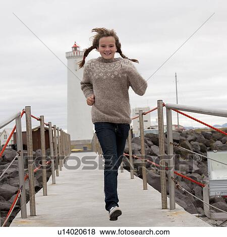 Stock Photo - Girl in braids running down railed walkway from lighthouse. Fotosearch