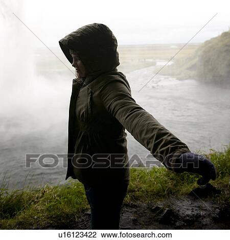 Girl in hooded coat standing in profile with arms spread before steamy body of water View Large Photo Image Stock Image - Girl in hooded coat standing in profile with arms spread before steamy body of water. Fotosearch