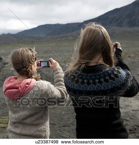 Stock Photo - Girl photographers at barren mountainside. Fotosearch
