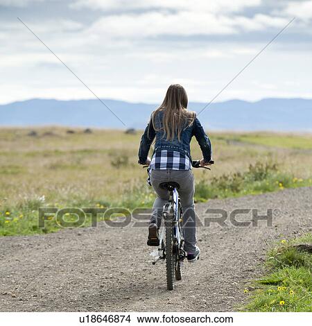Picture - Girl riding bicycle on unpaved country road. Fotosearch