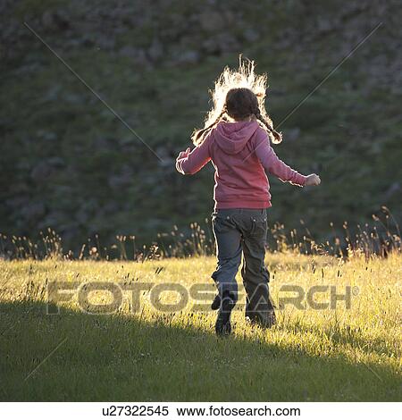 Girl running through a sunlit meadow View Large Photo Image Stock Photography - Girl running through a sunlit meadow. Fotosearch