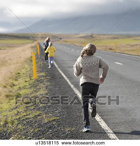 Stock Photography - Girls running away alongside the highway in the countryside. Fotosearch