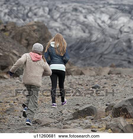 Stock Image - Girls walking away on glacial debris. Fotosearch