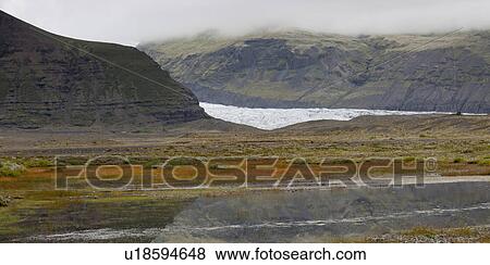 Glacier in misty rugged mountain valley, with water body reflecting the sky View Large Photo Image Stock Photo - Glacier in misty rugged mountain valley, with water body reflecting the sky. Fotosearch
