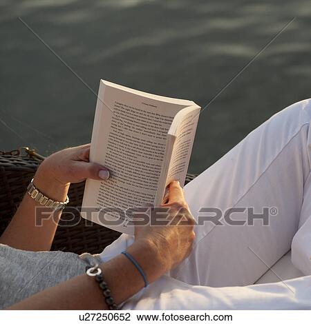 Stock Image - Hands holding a book at Lake of the Woods, Ontario. Fotosearch