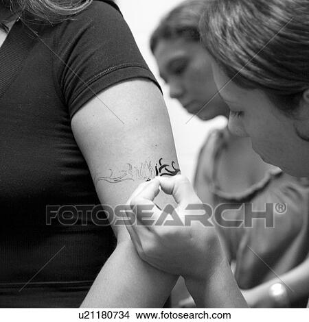 Picture - Henna Tattoo being drawn on a forearm. Fotosearch