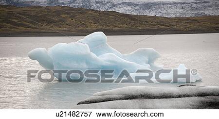 Iceberg melting in ocean water next to coastline View Large Photo Image Stock Photo - Iceberg melting in ocean water next to coastline. Fotosearch