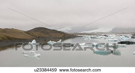 Icebergs floating in the ocean along a misty coastline View Large Photo Image Stock Photo - Icebergs floating in the ocean along a misty coastline. Fotosearch