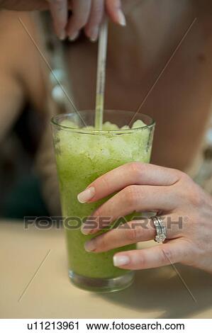 Iced green tea drunk through a straw by a woman with mainicured fingernails and diamond wedding and engagement rings View Large Photo Image Stock Image - Iced green tea drunk through a straw by a woman with mainicured fingernails and diamond wedding and engagement rings. Fotosearch