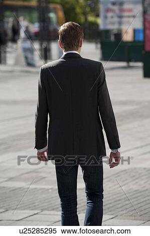 Stock Photography - Icelandic man in business suit and jacket walking on the city sidewalk, rear view. Fotosearch