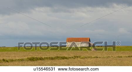 Stock Image - Landscape, farm building on the prairies, circular hay bale. Fotosearch