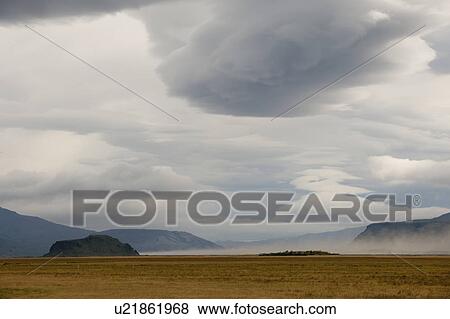 Landscape of barren meadow before mountains, with grey cloudy skies View Large Photo Image Stock Photo - Landscape of barren meadow before mountains, with grey cloudy skies. Fotosearch