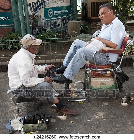 Stock Image - Man getting his shoes shined in San Jose Costa Rica. Fotosearch