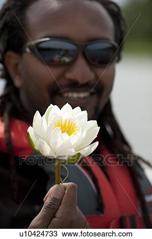 Stock Image - Man holding a white water lily. Fotosearch