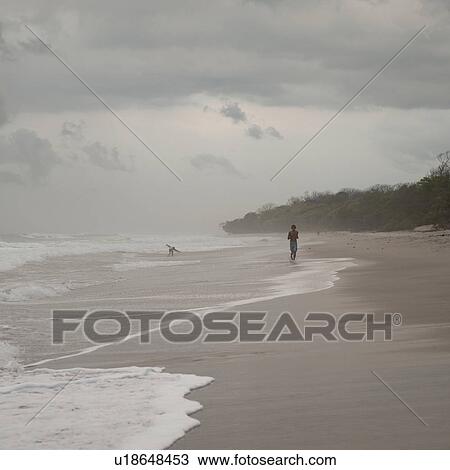 Stock Image - Man jogging along Coast Rica shoreline. Fotosearch