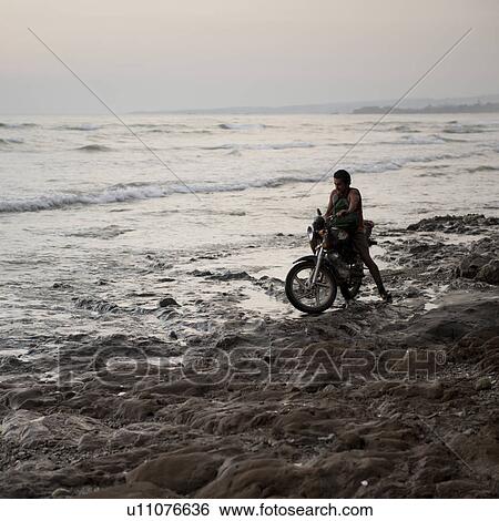 Stock Photograph - Man on a motorcycle along Costa Rica coastline. Fotosearch