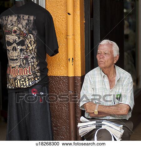 Stock Image - Man sitting in front of a store in San Jose Costa Rica. Fotosearch