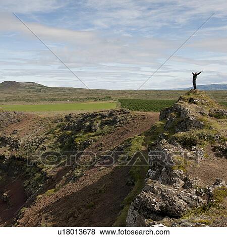 Man stretching with open arms on rocky hill outcrop above agricultural lands View Large Photo Image Stock Photo - Man stretching with open arms on rocky hill outcrop above agricultural lands. Fotosearch