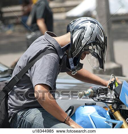 Stock Photography - Man wearing a helmet on a motorbike in Costa Rica. Fotosearch