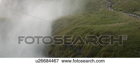 Stock Photo - Misty valley beside verdant hiking trail. Fotosearch