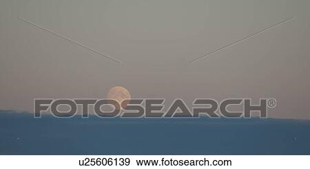 Stock Photo - Moon rising over the cloudy horizon. Fotosearch