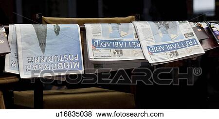 Stock Photo - Newspapers folded over rail at coffee shop. Fotosearch