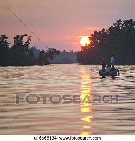 Picture - People in a boat at sunset in Lake of the Woods, Ontario. Fotosearch
