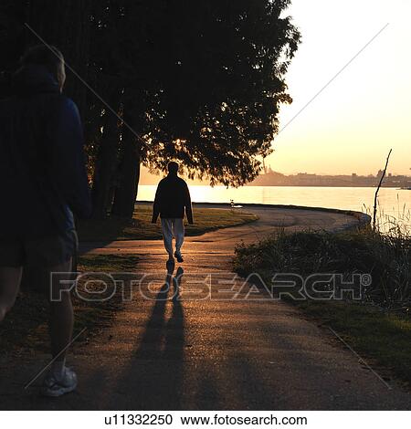People walking on the sea wall at dusk in Vancouver, British Columbia, Canada View Large Photo Image Stock Image - People walking on the sea wall at dusk in Vancouver, British Columbia, Canada. Fotosearch