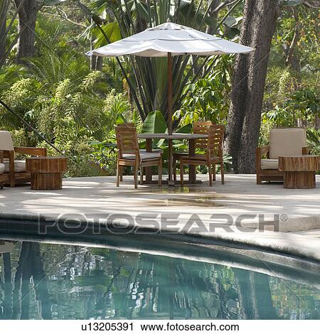 Stock Image - Poolside table and chairs in Costa Rica. Fotosearch