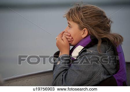 Stock Image - Profile of a young girl holding her hands over her mouth . Fotosearch