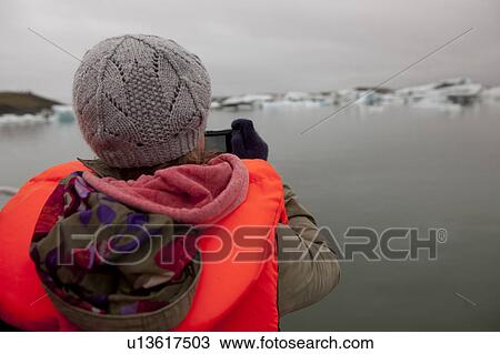 Rear view of girl in knit hat taking a photograph of icebergs in a glacial lake View Large Photo Image Stock Image - Rear view of girl in knit hat taking a photograph of icebergs in a glacial lake. Fotosearch