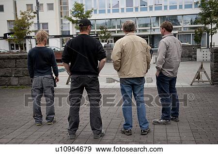 Stock Photo - Rear view of men standing on city sidewalk. Fotosearch