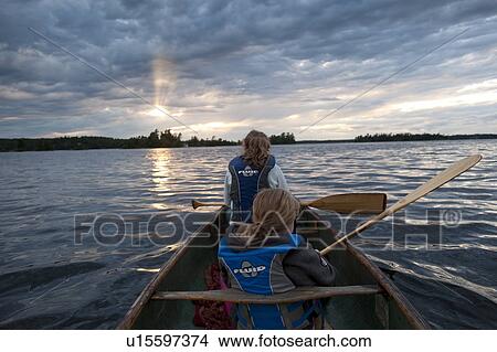 Picture - Rear view of two girls wearing life jackets in a canoe at Lake of the Woods, Ontario. Fotosearch