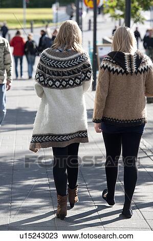 Stock Image - Rear view women wearing wool Icelandic sweaters on city sidewalk. Fotosearch