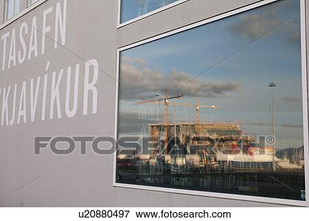 Stock Photo - Reflection in window of construction site and building cranes. Fotosearch