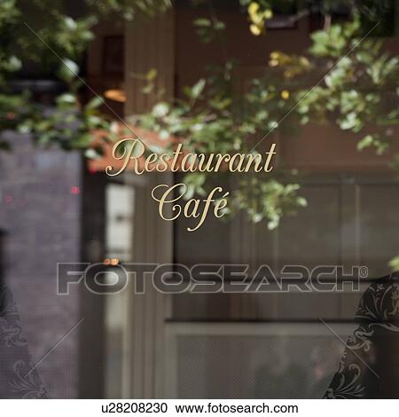 Stock Image - Reflection of tree and office building in signage window of restaurant. Fotosearch