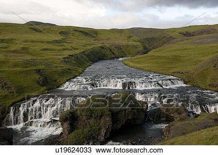 Stock Image - River eroded into hilly pastureland, with whitewater steps. Fotosearch