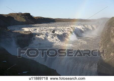 Stock Photo - River flowing over rocks creating waterfall and rainbow. Fotosearch
