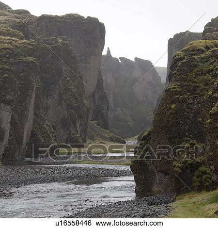 Stock Photograph - River running past steep rugged cliffs. Fotosearch