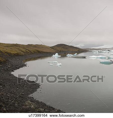 Picture - Rocky beach on glacial lake with floating icebergs. Fotosearch